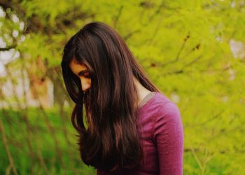 A women looking down to her feet while her hair covers her side-profile.