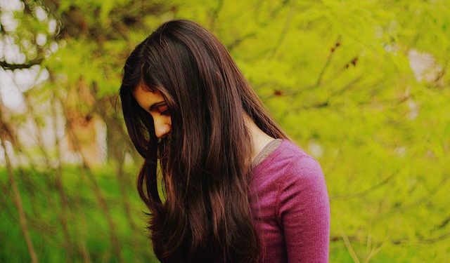 A women looking down to her feet while her hair covers her side-profile.