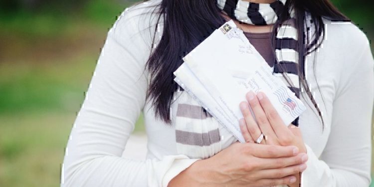 A women holding up letters to send to her husband.