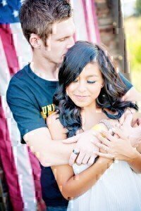 A couple that is holding each other while the man kisses the women's head.