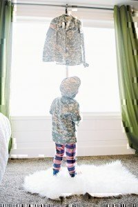 A young child looking up at a shift that is hanging in front of a window.