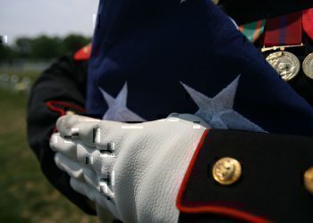 A folded national ensign is held carefully prior to the burial of Maj. Douglas A. Zembiec, former commander of E Company, 2nd Battalion, 1st Marine Regiment.  Zembiec was killed in action May 10.  He once told reporters during combat in Fallujah his Marines "fought like lions."  Zembiec was laid to rest by the Marine with whom he served May 15.