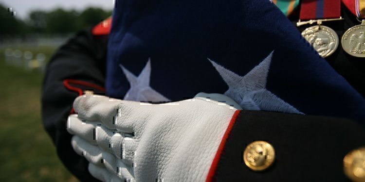 A folded national ensign is held carefully prior to the burial of Maj. Douglas A. Zembiec, former commander of E Company, 2nd Battalion, 1st Marine Regiment.  Zembiec was killed in action May 10.  He once told reporters during combat in Fallujah his Marines "fought like lions."  Zembiec was laid to rest by the Marine with whom he served May 15.