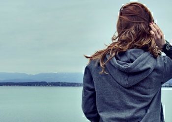 A women fixing her hair while looking out over the water.