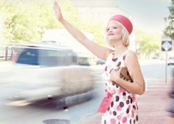 A women reaching out her hand to grab the attention of a taxi driver.