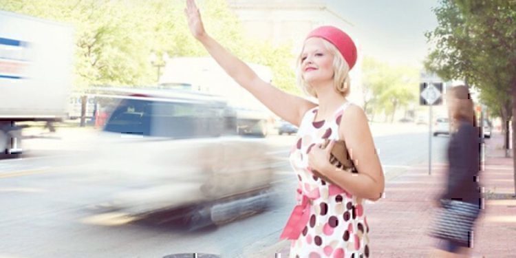 A women reaching out her hand to grab the attention of a taxi driver.