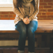 A young women sitting on a table with her hands folded.