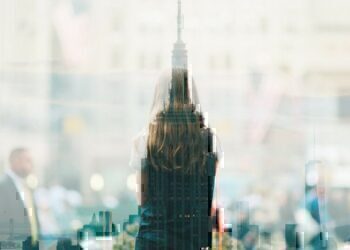 The top of a skyscraper that has a silhouette of a young women at the forefront.