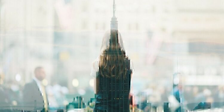 The top of a skyscraper that has a silhouette of a young women at the forefront.