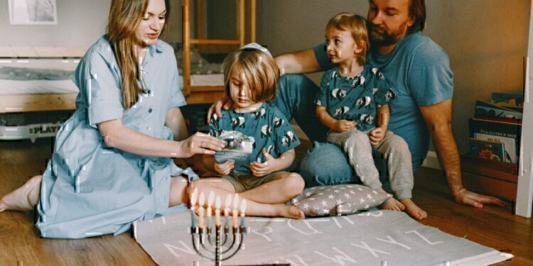 A family seated on the floor, celebrating hanukkah together.