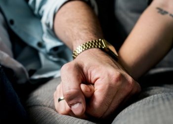 A couple holding hands while sitting on a couch.