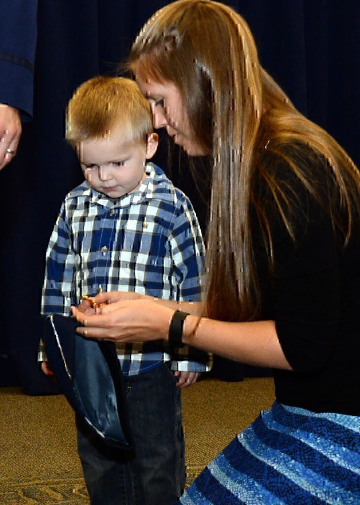 A military wife with her son looking at a badge that is going to be placed on her husbands uniform.