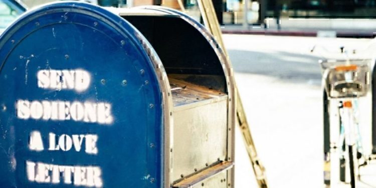 A rusted mailbox that is on the side of the street.