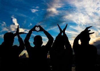 Four people sitting down spelling out the word love with their hands.