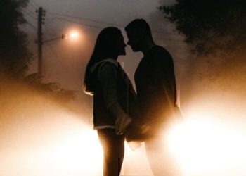 A young couple holding hands while looking into each others eyes.