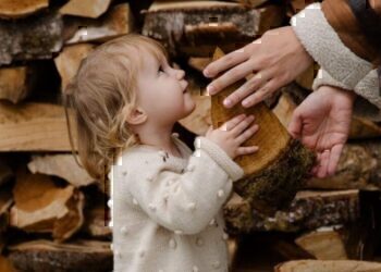 A child handing a piece of wood to her parent.