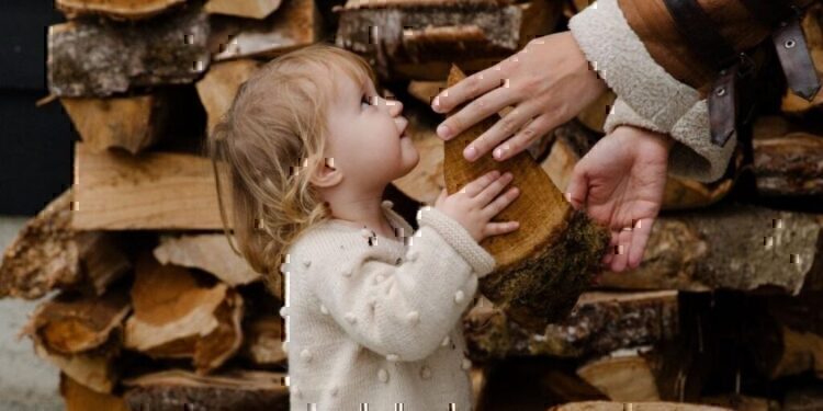 A child handing a piece of wood to her parent.