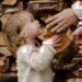 A child handing a piece of wood to her parent.