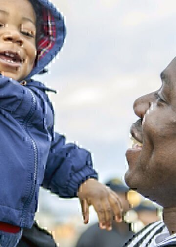 A Navy seamen lovingly picks up his smiling baby boy after coming home from deployment