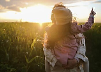 Mom holding a daughter in a field at sunset thinking about planning her estate