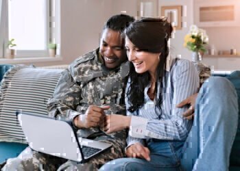 Military Spouse sitting on the couch with her husband looking for online programs by Carrus.