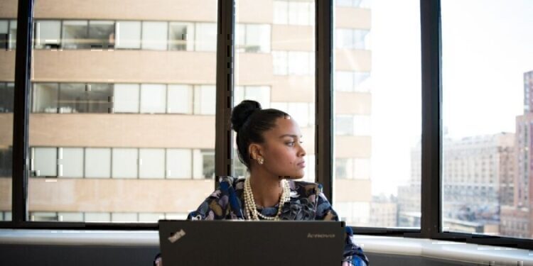 A working women briefly looking away from her computer and out of the window.