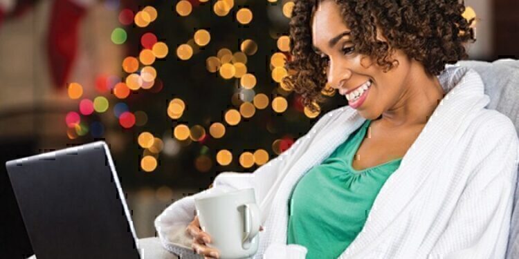 A mother looking at her computer as she shops for her family's Christmas gifts.