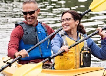 Two healthy couples who use Blue Cross Blue Shield for their vision insurance are paddling down the river in a kayak.