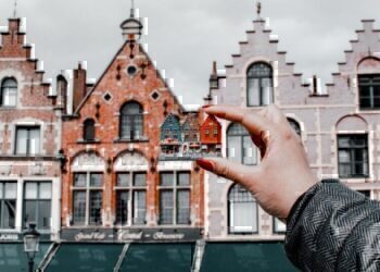 Someone's hand holding up a set of little homes, compared to bigger homes.