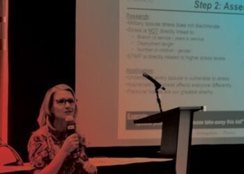 A women sitting down at a conference, talking about mental health.