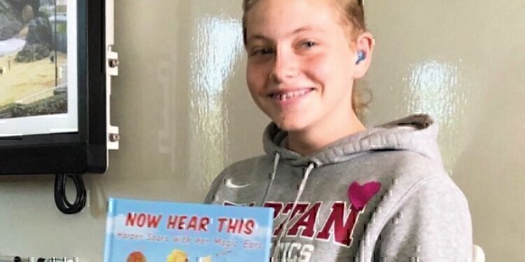 Haper holding up a book and smiling for the camera!