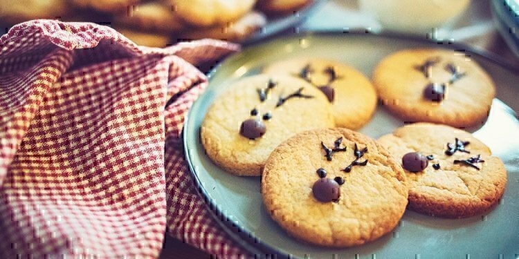 Five rain-deer cookies that are sitting on a blue plate.