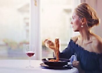 A women looking out of her window while eating her lunch alone.