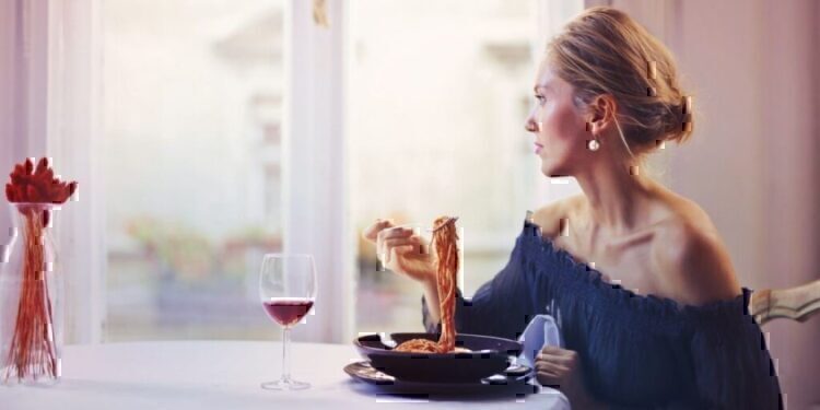 A women looking out of her window while eating her lunch alone.