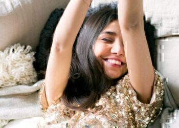 A women laying down on a couch, smiling and enjoying the new year.