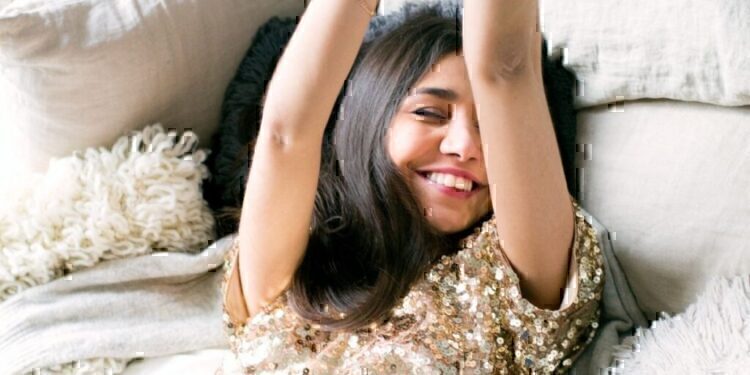 A women laying down on a couch, smiling and enjoying the new year.