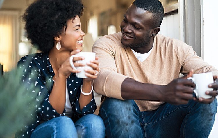 A married man and women smiling each other while drinking coffee.