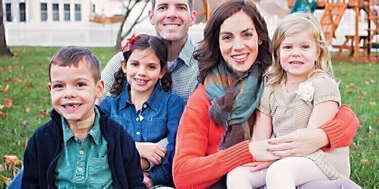 The Benscoter family sitting on green grass, smiling for the photograph.