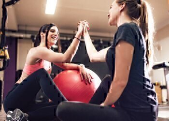 Two women high-fiving each other after completing a hard workout.