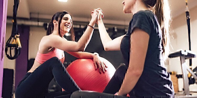 Two women high-fiving each other after completing a hard workout.