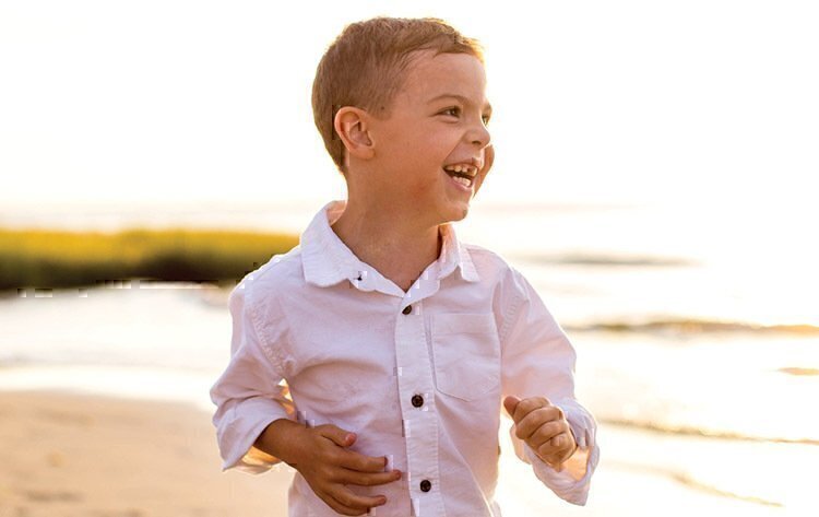 Tyler Benscoter running down the beach while smiling and laughing.