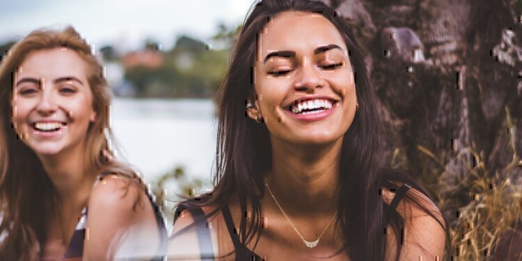 Two women sitting and smiling with each other.